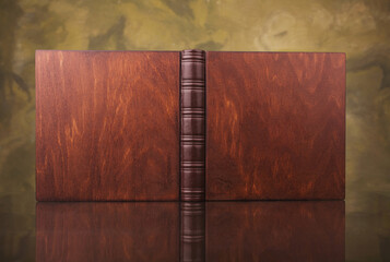 Family photo book with wooden cover. Opened Photo book on a green abstract blured background. Brown...