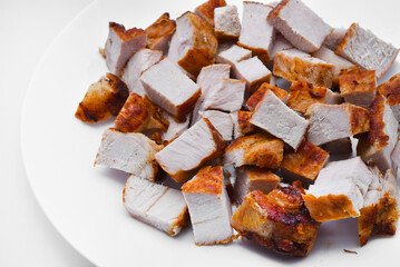 Pieces of fried pork meat on a white plate. Juicy and delicious pieces of barbecue meat.