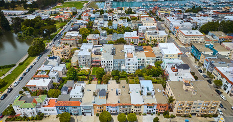 Block of apartment buildings surrounding green backyards wide aerial with boats in San Francisco Bay, CA