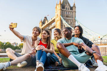 Multiracial group of happy young friends bonding in London city - Multiethnic teens students meeting and having fun in Tower Bridge area, UK - Concepts about youth lifestyle, travel and tourism - obrazy, fototapety, plakaty