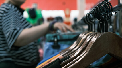Naklejka premium hangers with clothes in the store, in the background a girl chooses clothes
