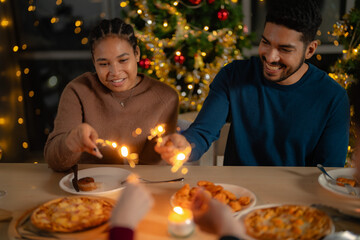 men and women holding sparkler fireworks in a party with Christmas tree. young couple Asian people enjoy celebrating Christmas and New Year. happy and celebrate with food wine and friendship for love,