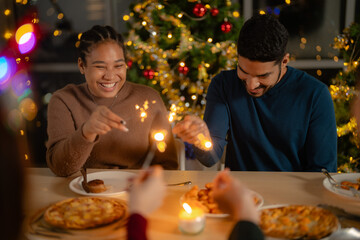 men and women holding sparkler fireworks in a party with Christmas tree. young couple Asian people enjoy celebrating Christmas and New Year. happy and celebrate with food wine and friendship for love,