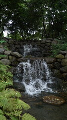 Fototapeta na wymiar Small artificial waterfall in the park