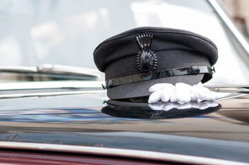 A chauffeur peaked cap with white gloves sitting on a car