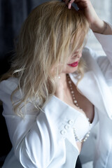 blonde in a white jacket puts on beads