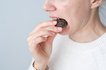 Close up an unrecognizable person biting a chocolate. Unhealthy eating. Dental health concept. High quality photo - obrazy, fototapety, plakaty