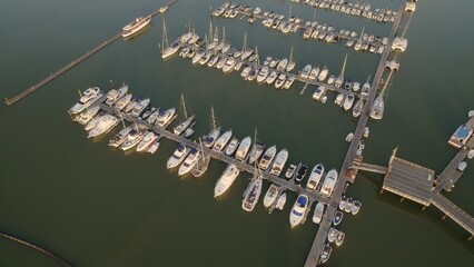 Sunrise at the marina. Boats in the estuary with the sea in the background. Aerial view from drone with many boats of different types. El Rompido. Huelva. Andalusia. Spain. - obrazy, fototapety, plakaty