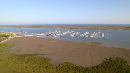 Sunset at the marina. Boats in the estuary with the sea in the background. Aerial view marshes with many boats of different types. El Rompido. Huelva. Andalusia. Spain.