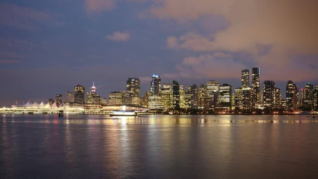 View of buildings illuminated in the city on coastline from stanley park at Vancouver