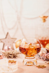 Glass of whiskey or bourbon with festive Christmas decoration on light beige background. New Year, Christmas and winter holidays whiskey mood concept