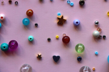 Various colorful beads on bright pink background. Top view.