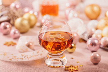 Glass of whiskey or bourbon with festive Christmas decoration on light background. New Year, Christmas and winter holidays whiskey mood concept