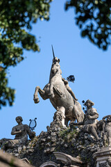 Equestrian statue of a unicorn with raised front legs framed between tree leaves