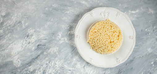 Boiled Ptitim Israeli pasta on a light background Long banner format. top view. copy space for text