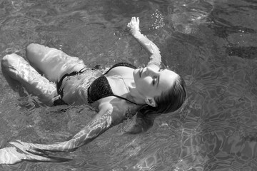 Fototapeta premium Woman in the pool. Concept of recreation and relaxing. Beautiful lady at weekend taking sunbath