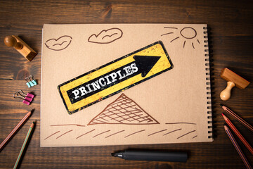 Principles. Pointing arrow and stationery on wooden office table