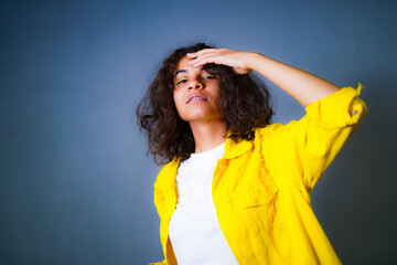 A woman in a yellow jacket is holding her hands on her head. A Woman in a Vibrant Yellow Jacket...