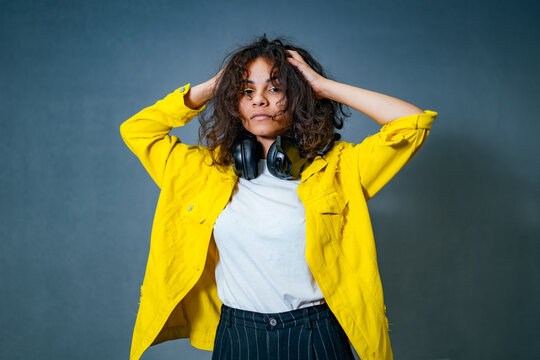 A woman wearing headphones and a yellow jacket. A Serene Music Lover Enjoying Melodies in a Vibrant Yellow Jacket - Powered by Adobe