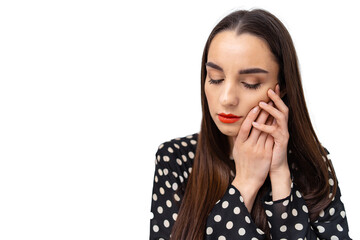 A woman in a polka dot shirt holding her hand to her face. A Woman in a Polka Dot Shirt Expressing...