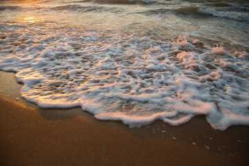 The sea, shimmering with gold from the dawn sun, the water's edge and the shore.