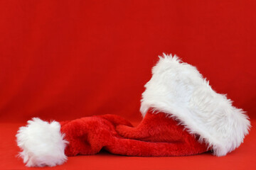Obraz na płótnie Canvas Red and white fur Santa Hat on a simple red background 