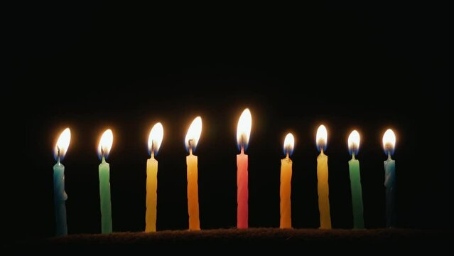 Hanukkah is a Jewish religious holiday of candles. Nine burning candles on dark background. The Feast of Fire and Light