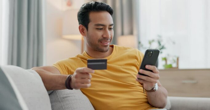Man, credit card and phone for home online shopping, e commerce payment and subscription on sofa. Young, happy asian person relax on couch, mobile banking and loan application for streaming service