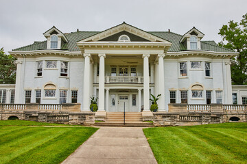 Large white estate with sidewalk leading to pillars and front door under balcony, Muncie, IN