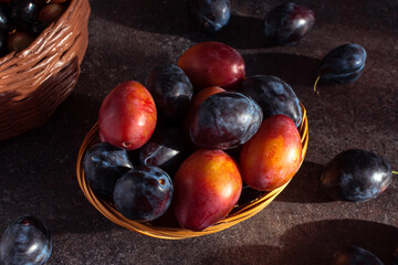 plums in a basket on a dark table