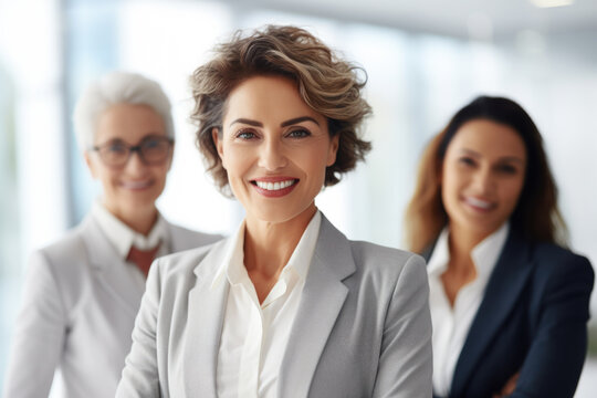 Woman standing confidently in front of three other women. This versatile image can be used to represent leadership, teamwork, diversity, or friendship.