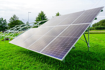 Installation of solar panels on metal frames in a green meadow, unfinished solar power plant