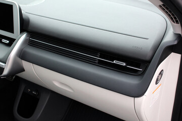 Modern car passenger airbag. Glove compartment in white car interior. Detail of new electric car interior. White leather interior.
