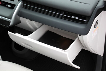 Open glove box. Modern car passenger airbag. Glove compartment in white car interior. Detail of new...