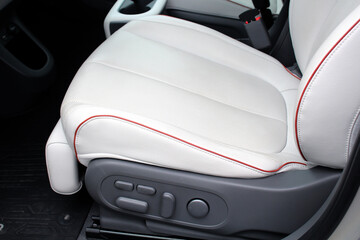 White leather driver seat with perforations and red stitching. interior of a modern car with white...