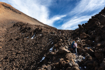 Tourists climb the Teide volcano. Path along the lava fields.