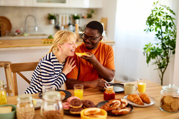 Multiracial couple enjoying breakfast together at home