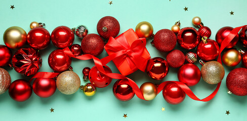 Christmas balls and gift box on turquoise background, top view