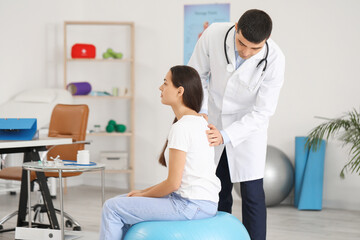 Fototapeta premium Male doctor checking posture of young woman in clinic