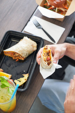 Friends eating takeout food at table focus on burrito