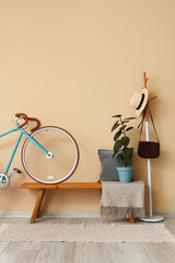 Wooden bench with bicycle, rack and houseplant in hallway