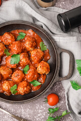 Frying pan of tasty meat balls with tomato sauce and parsley on grey background