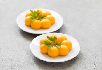 Carrot cream dessert, Panna Cotta in the shape of truffles, with parsley. On a plate. LIght grey background. Close up	