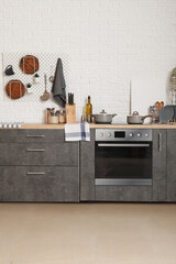 Grey counters with cutting boards, utensils, oven and electric stove in modern kitchen