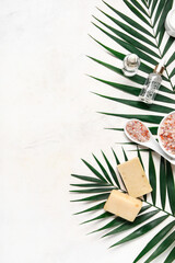 Composition with bath supplies and palm leaves on light background