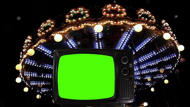 Old Television Turning On Green Screen Against A Merry Go Round At Night. 4K Resolution.