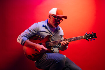 Obraz premium Man playing electric guitar on red background