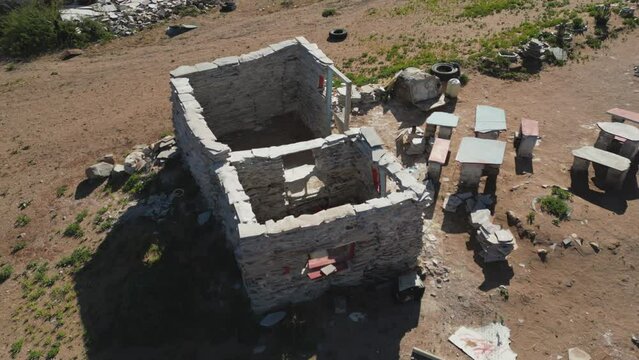 Look down onto small roofless building surrounded by picnic tables made from quartzite tiles