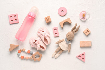 Stylish baby shoes with toys, pacifier, rattle and bottle of milk on grunge white background