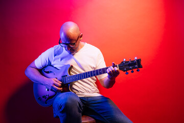 Man playing electric guitar on red background